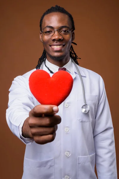 Joven guapo africano hombre médico contra marrón fondo —  Fotos de Stock