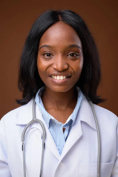 Young beautiful African Zulu woman doctor against brown backgrou — Stock Photo, Image