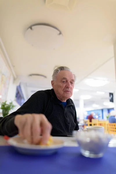 Senior man eating at the cafeteria in nursing home — Stock Photo, Image