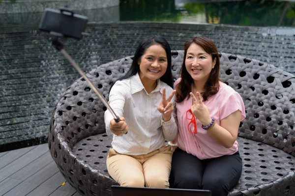 Bangkok 'taki alışveriş merkezinin dışında iki olgun Asyalı kadının portresi.