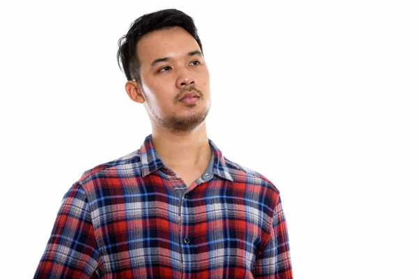 Studio shot of young Asian man thinking while looking up — Stock Photo, Image