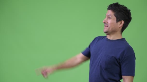 Vista del perfil del hombre hispano sonriendo mientras señala con el dedo — Vídeos de Stock