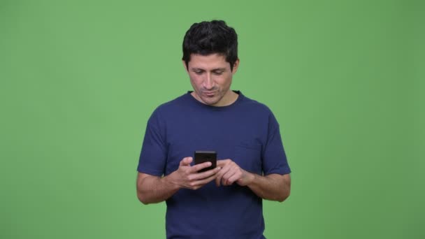 Lycklig spansktalande man tänker medan du använder telefonen — Stockvideo
