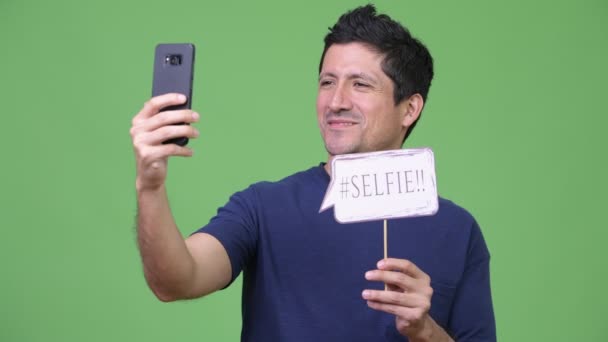 Hombre hispano tomando selfie con cartel de papel — Vídeo de stock