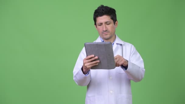 Hispanic man doctor thinking while using digital tablet — Stock Video