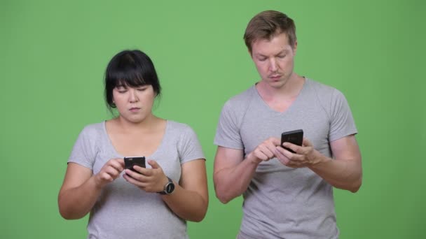 Young multi-ethnic couple using phone and thinking together — Stock Video