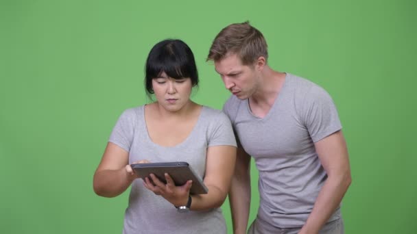 Молодая многонациональная пара, использующая цифровой планшет и получающая хорошие новости вместе — стоковое видео