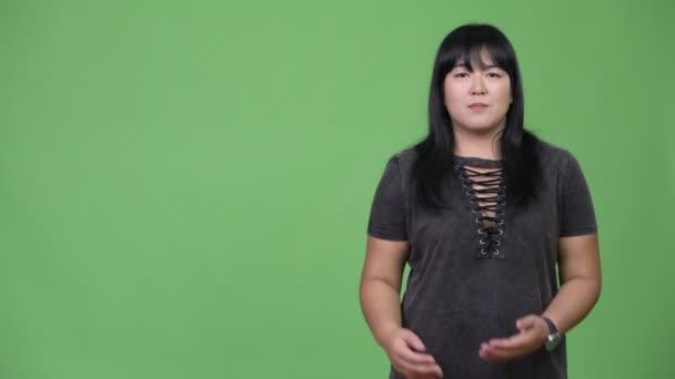 Счастливая азиатская женщина с лишним весом что-то показывает — стоковое видео