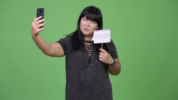 Belle femme asiatique en surpoids prenant selfie avec signe en papier — Video