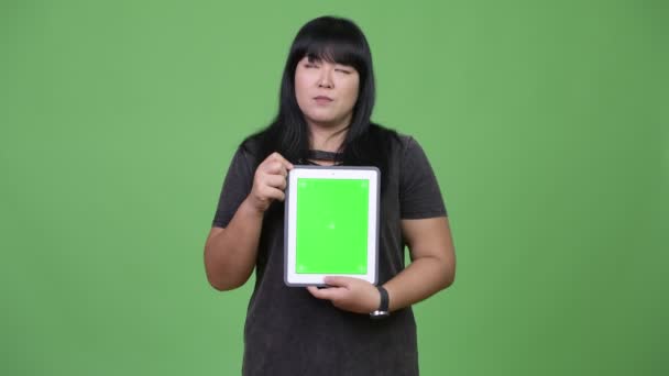 Happy nadváhu asijských žena myslet při zobrazování digitálních tabletu — Stock video
