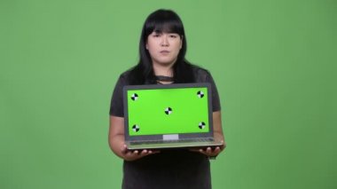 Dizüstü bilgisayarı gösteren süre düşünerek mutlu kilolu Asyalı kadın