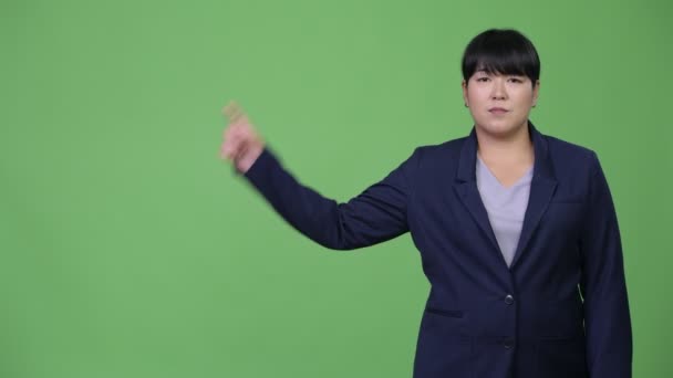 Happy overweight Asian businesswoman thinking while pointing up — Stock Video