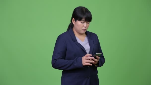 Feliz sobrepeso asiático mujer de negocios pensando mientras se utiliza el teléfono — Vídeo de stock