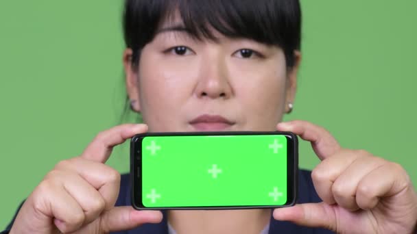 Счастливая толстая азиатская деловая женщина показывает телефон — стоковое видео
