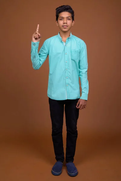 Молодий індійський хлопчик носіння блакитній сорочці дивлячись смарт проти Браун — стокове фото