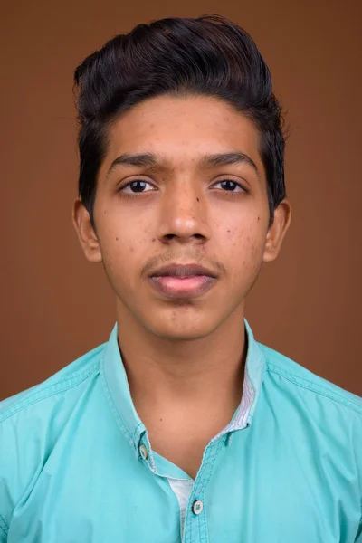 Jovem indiana menino vestindo azul camisa olhando inteligente contra marrom — Fotografia de Stock