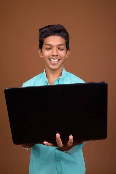 Jovem indiana menino vestindo azul camisa olhando inteligente contra marrom — Fotografia de Stock