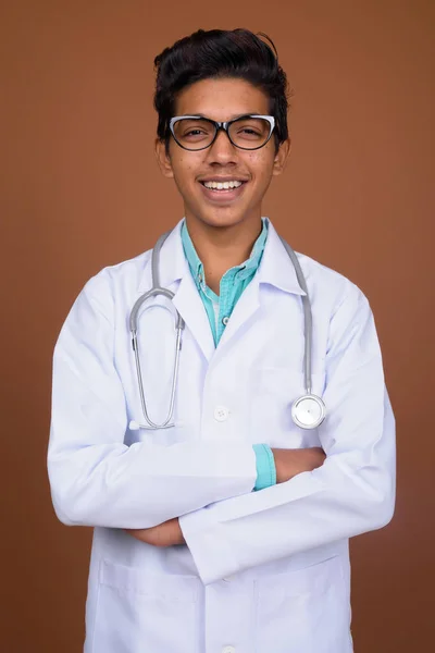 Νεαρό αγόρι ινδική γιατρός φοράει γυαλιά εναντίον καφέ backgro — Φωτογραφία Αρχείου