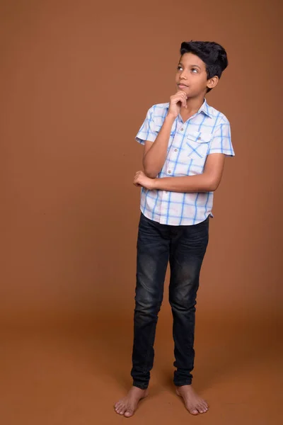 Jovem indiana menino vestindo xadrez camisa contra marrom backgroun — Fotografia de Stock