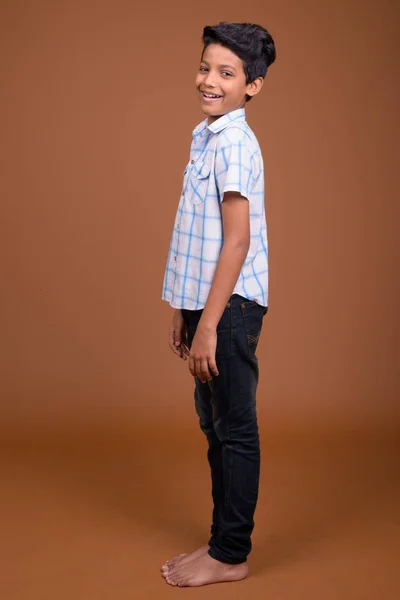 Jovem indiana menino vestindo xadrez camisa contra marrom backgroun — Fotografia de Stock