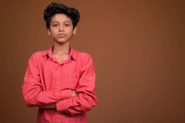 Young Indian boy wearing smart casual clothing against brown bac