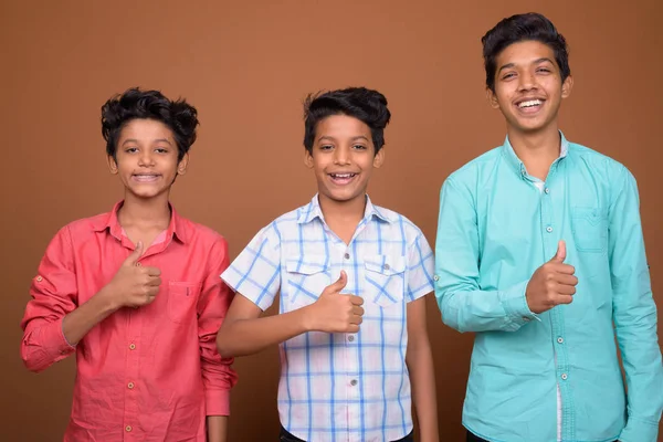 Drei junge indische Brüder gemeinsam vor braunem Hintergrund — Stockfoto