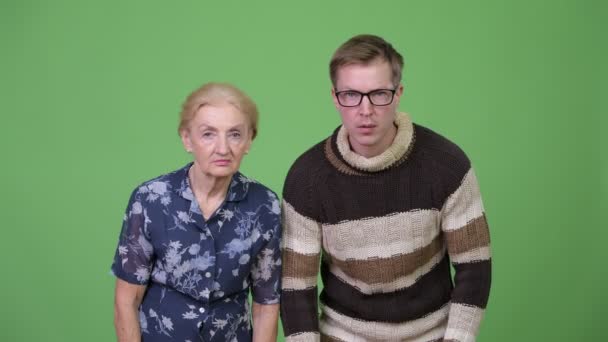 Großmutter feiert, während Enkel sich vor grünem Hintergrund aufregt — Stockvideo