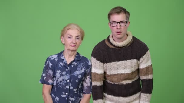 Großmutter und Enkel sehen frustriert aus, während sie ihr Gesicht zusammen verdecken