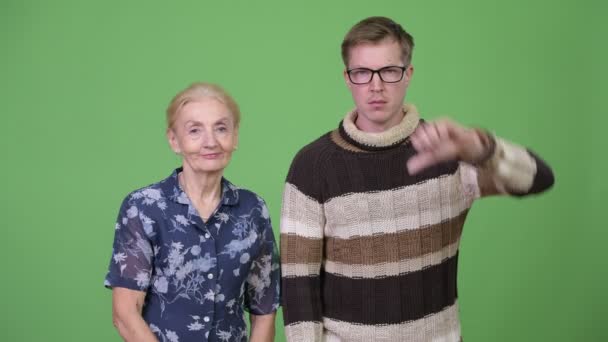Feliz abuela dando pulgares hacia arriba mientras molesto nieto dando pulgares hacia abajo — Vídeos de Stock