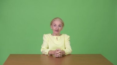 Ahşap masa karşı bir şey sunmak güzel üst düzey iş kadını