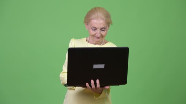 Schöne glückliche Seniorin denkt, während sie Laptop benutzt — Stockvideo