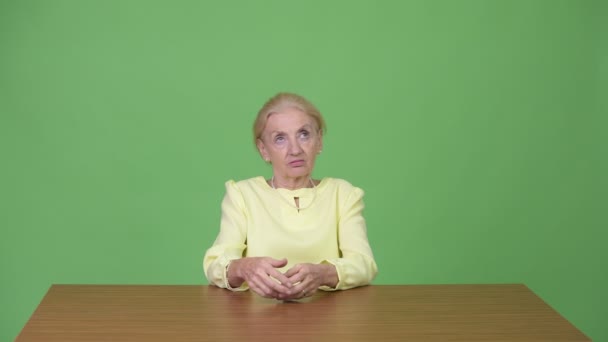 Piękna kobieta interesu starszy patrząc nudzić przed drewnianym stole — Wideo stockowe