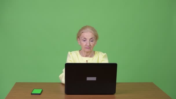 Schöne Seniorin mit Telefon und Laptop — Stockvideo