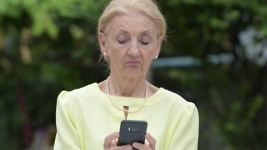 Telefon açık havada kullanırken gülümseyen güzel mutlu üst düzey iş kadını
