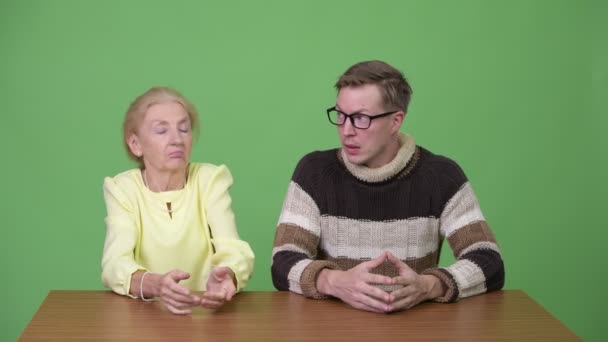 Старшая деловая женщина сходит с ума с молодым человеком, который выглядит смущенным — стоковое видео
