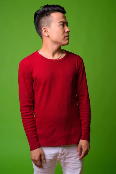 Multi-etnische jongeman dragen rode trui tegen groene achtergrond — Stockfoto
