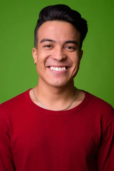 Joven hombre multiétnico con suéter rojo sobre fondo verde —  Fotos de Stock