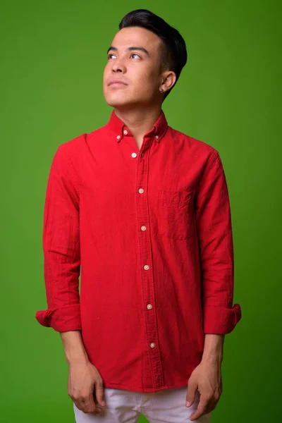 Молодий багатоетнічний бізнесмен у червоній сорочці на зеленому фоні — стокове фото