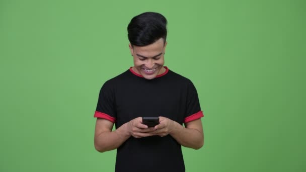 Joven feliz hombre multiétnico pensando mientras usa el teléfono — Vídeo de stock
