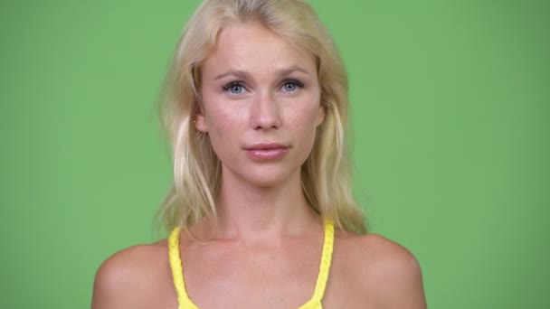 Νεαρή όμορφη γυναίκα με ξανθά μαλλιά πράσινο φόντο — Αρχείο Βίντεο