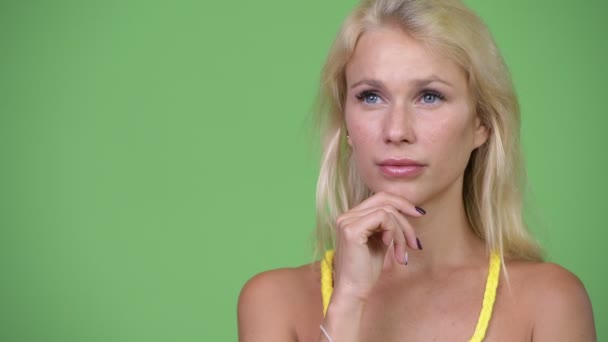Junge glückliche schöne blonde Frau lächelt beim Nachdenken — Stockvideo