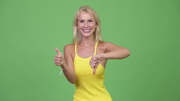 Młodych mylić piękne blond kobieta wybór między kciuk w górę i dół — Wideo stockowe