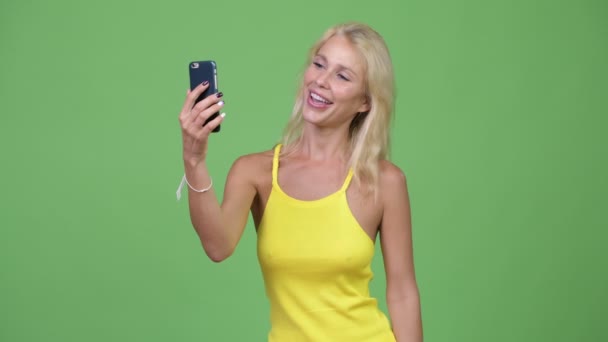 Junge glückliche schöne blonde Frau Videotelefonie und zeigt Telefon — Stockvideo