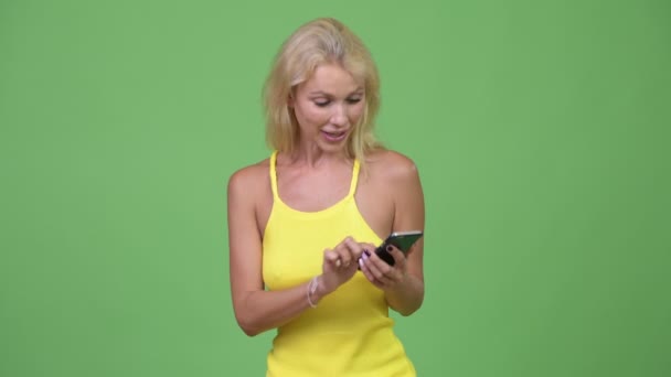 Jeune femme blonde heureuse utilisant le téléphone et obtenir de bonnes nouvelles — Video