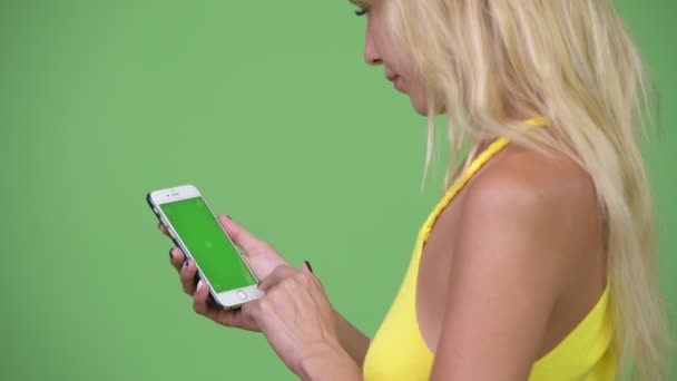Ung vacker blond kvinna med telefonen mot grön bakgrund — Stockvideo