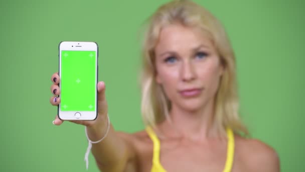 Mutlu güzel sarışın genç kadın gösteren telefon — Stok video