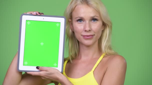 젊은 행복 한 아름 다운 금발의 여 자가 보여주는 디지털 태블릿 — 비디오