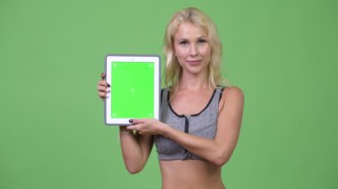 Dijital tablet spor salonu için hazır gösterilen genç mutlu güzel kadın
