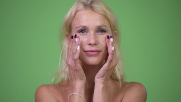Kopfschuss einer jungen schönen blonden Frau ohne Hemd, während sie ihr Gesicht berührt — Stockvideo