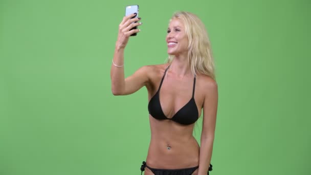 Gelukkig jonge mooie blonde vrouw die het dragen van bikini terwijl videobellen — Stockvideo
